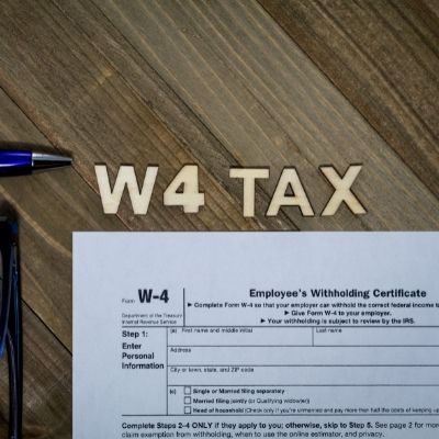 W4 tax written in the wood of a desk and the w-4 tax document sitting just below the engraving 