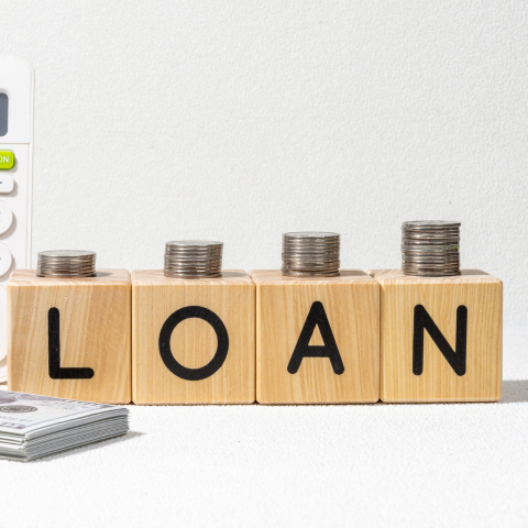 Person using a calculator while reviewing installment loan paperwork