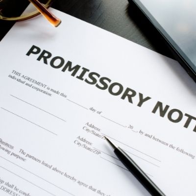 Borrower signature line on a promissory note beside a pen