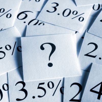 Person comparing interest rates and loan costs with a calculator and laptop