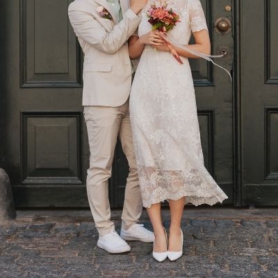Couple in wedding attire holding a bouquet outside a venue