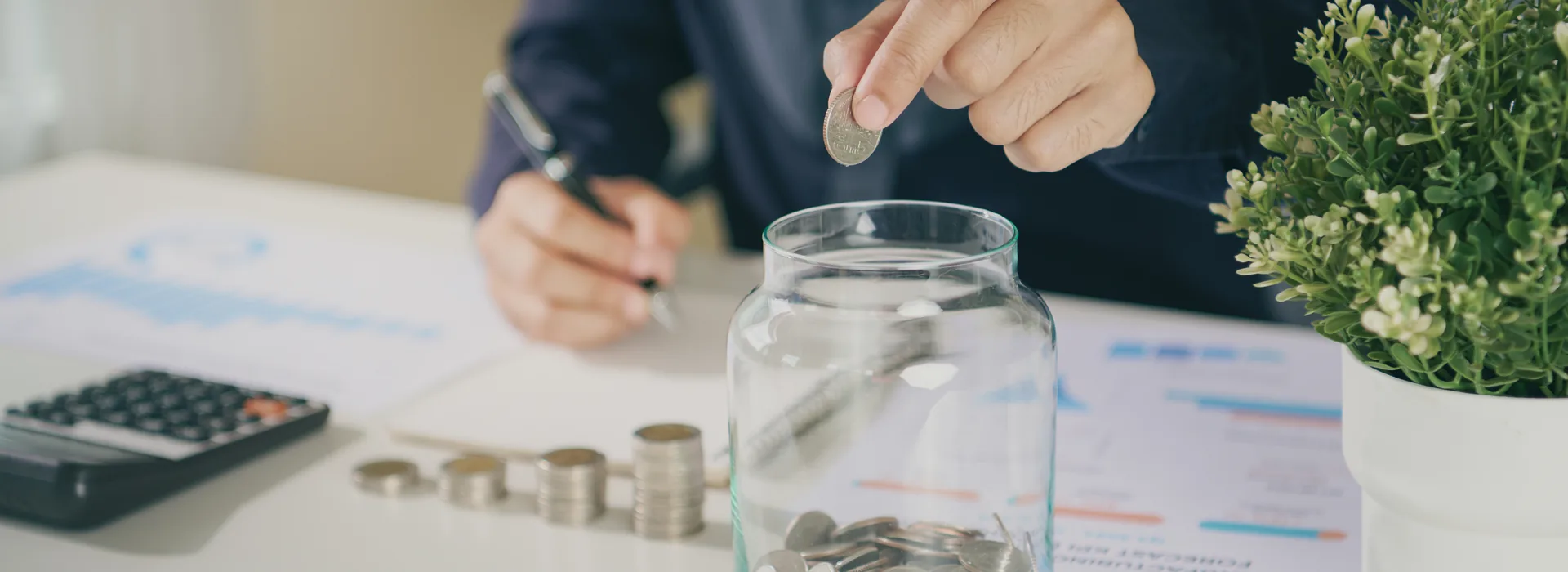 Person placing a coin into an emergency savings jar