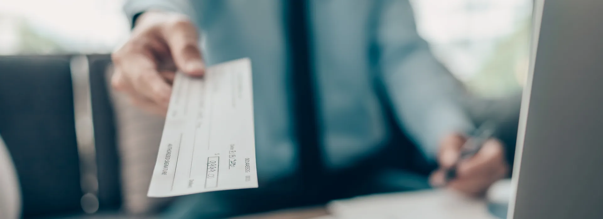 Person handing a check to a customer beside U.S. cash
