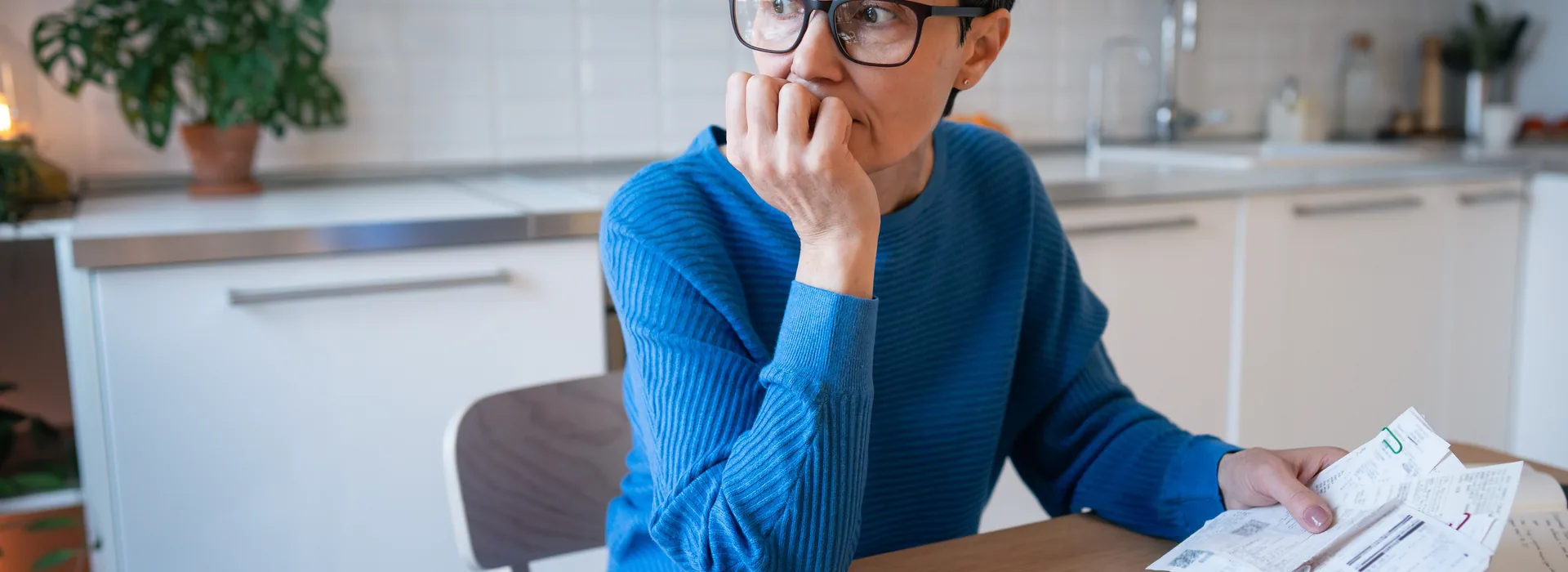 Stressed mature woman surrounded by bills and receipts