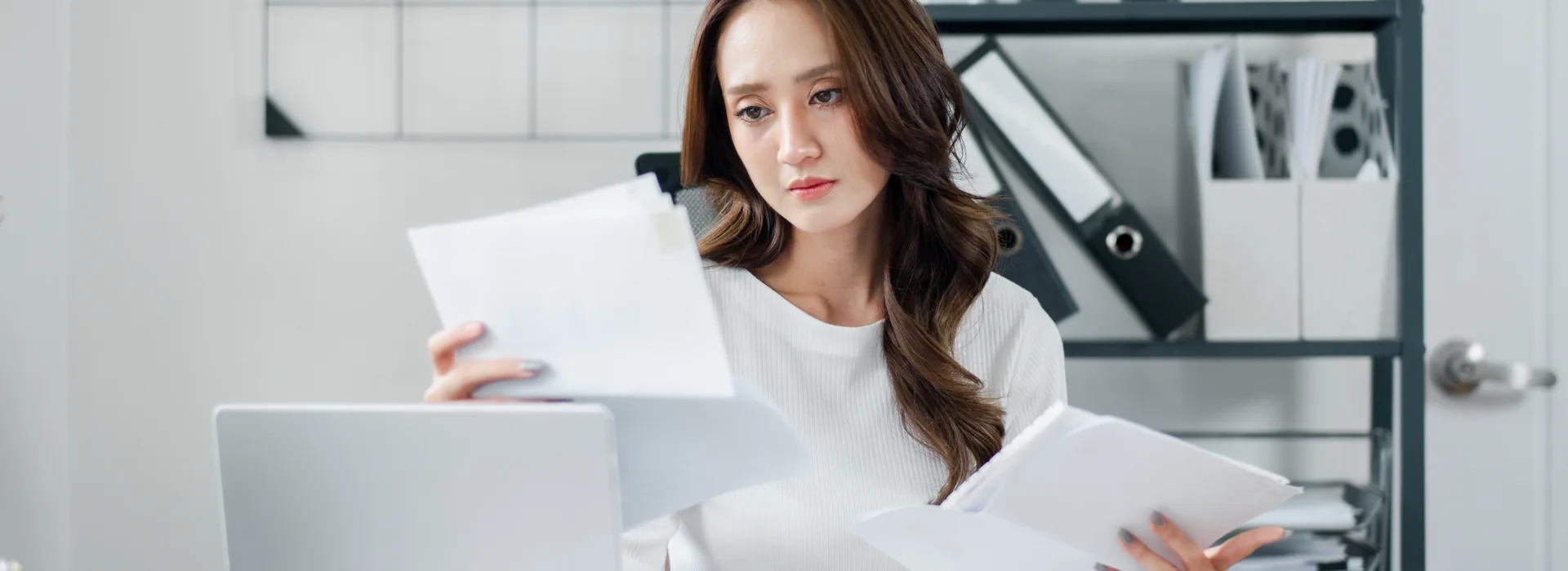 Self-employed woman organizing multiple financial documents at her workspace