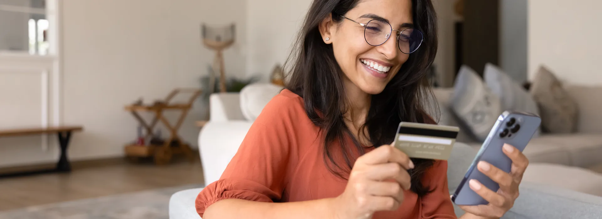 Woman holding a debit card while using a smartphone at home