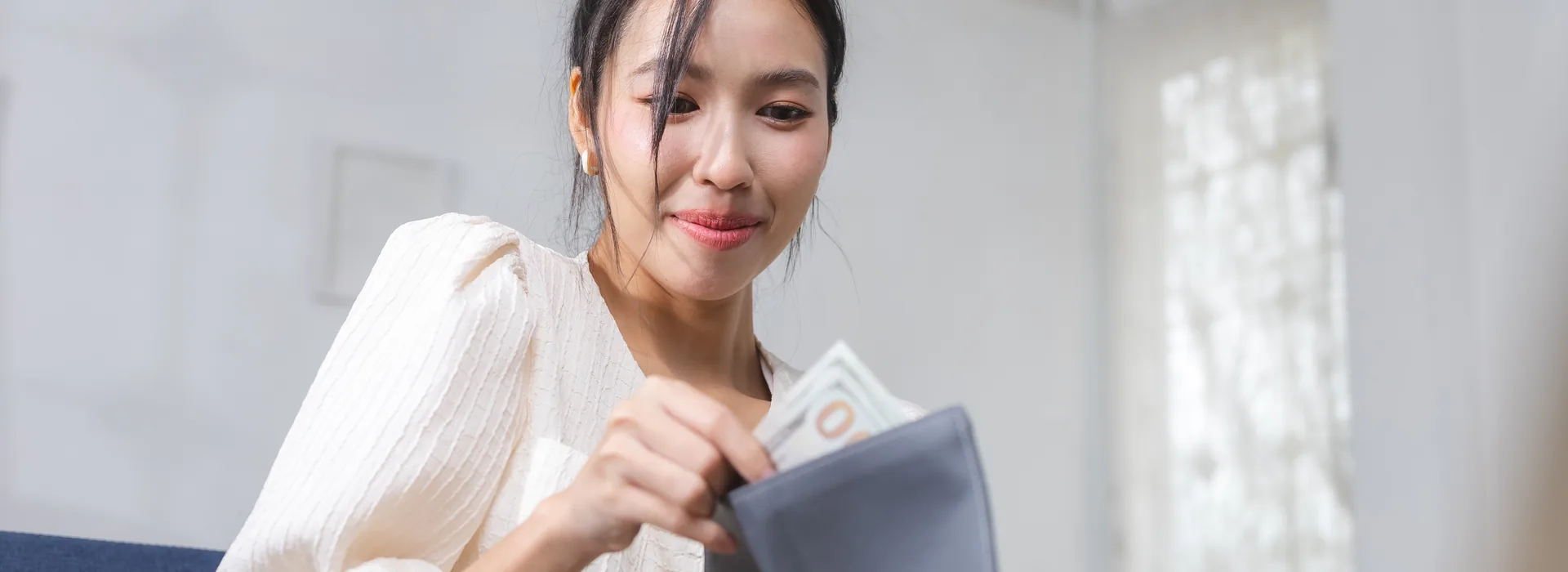 Woman budgeting cash from a wallet at home