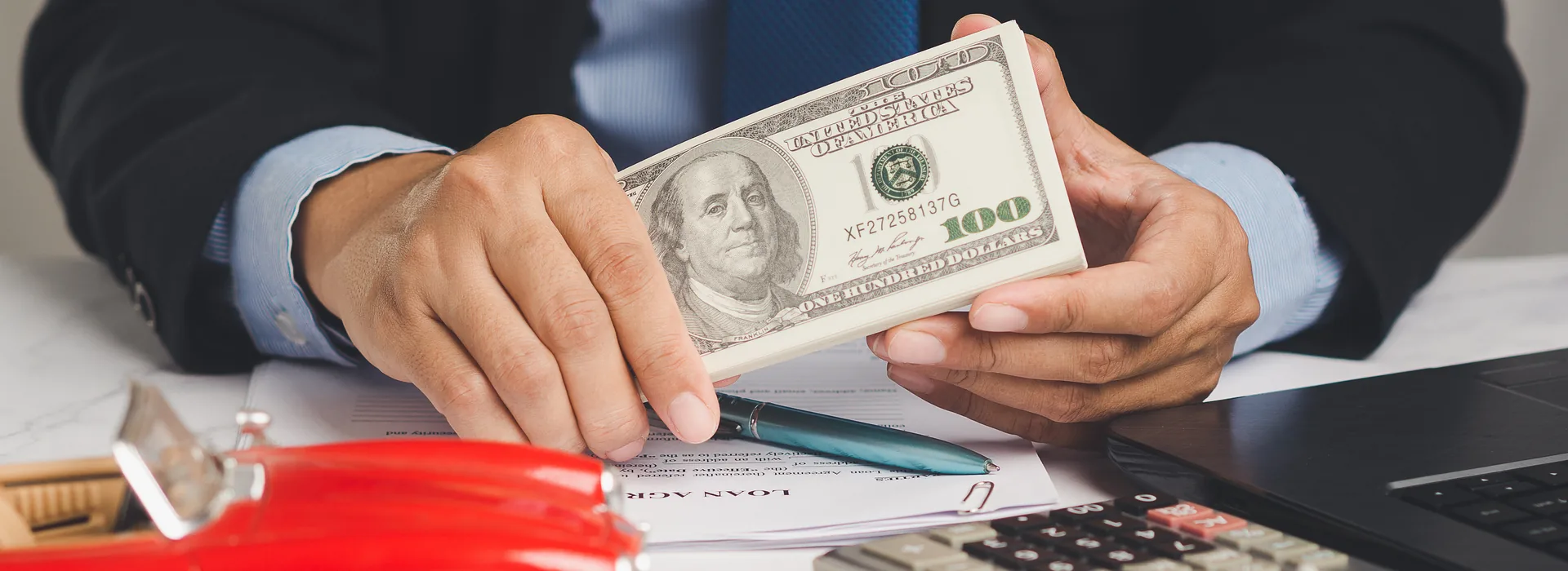 Borrower holding cash beside a toy car while reviewing title loan paperwork