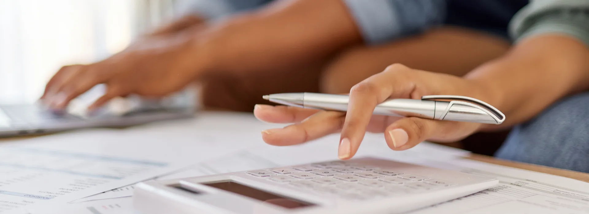 Person using a calculator while reviewing household loan paperwork