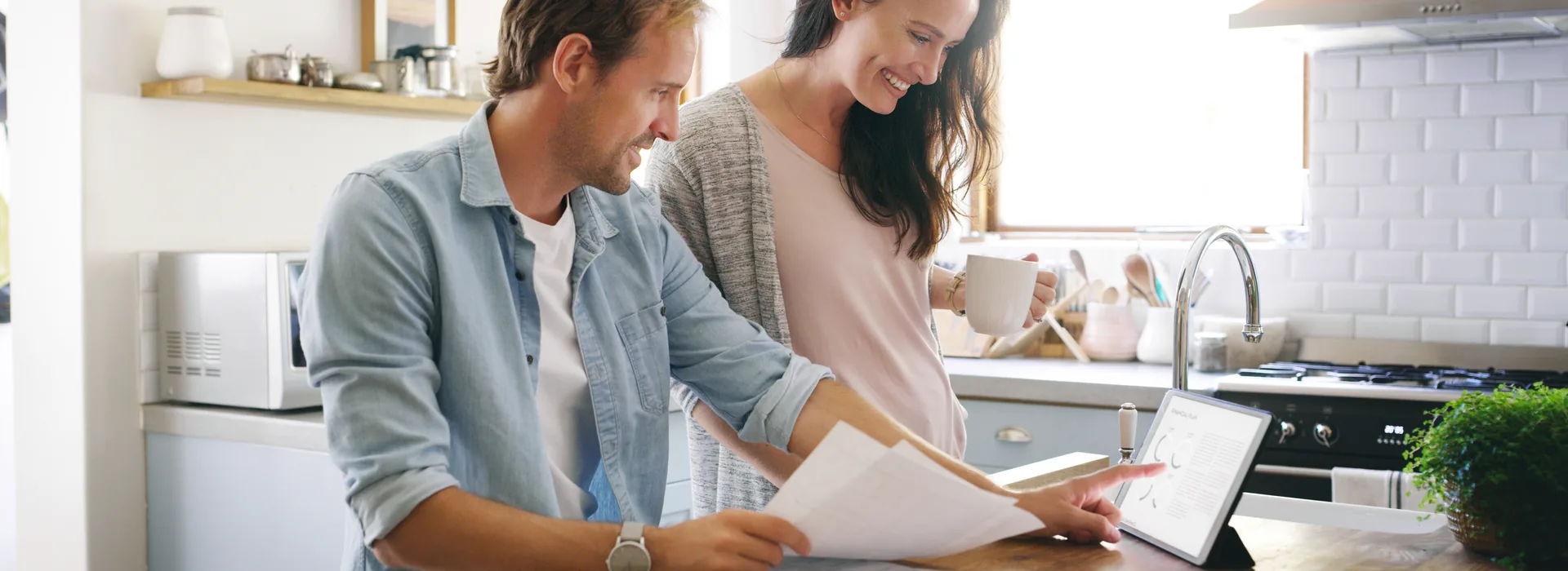 Couple reviewing bills and financial information on a tablet at home