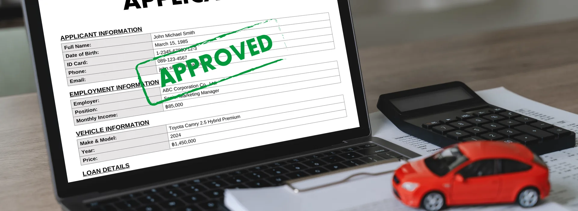 Approved car loan application displayed on a laptop beside a calculator