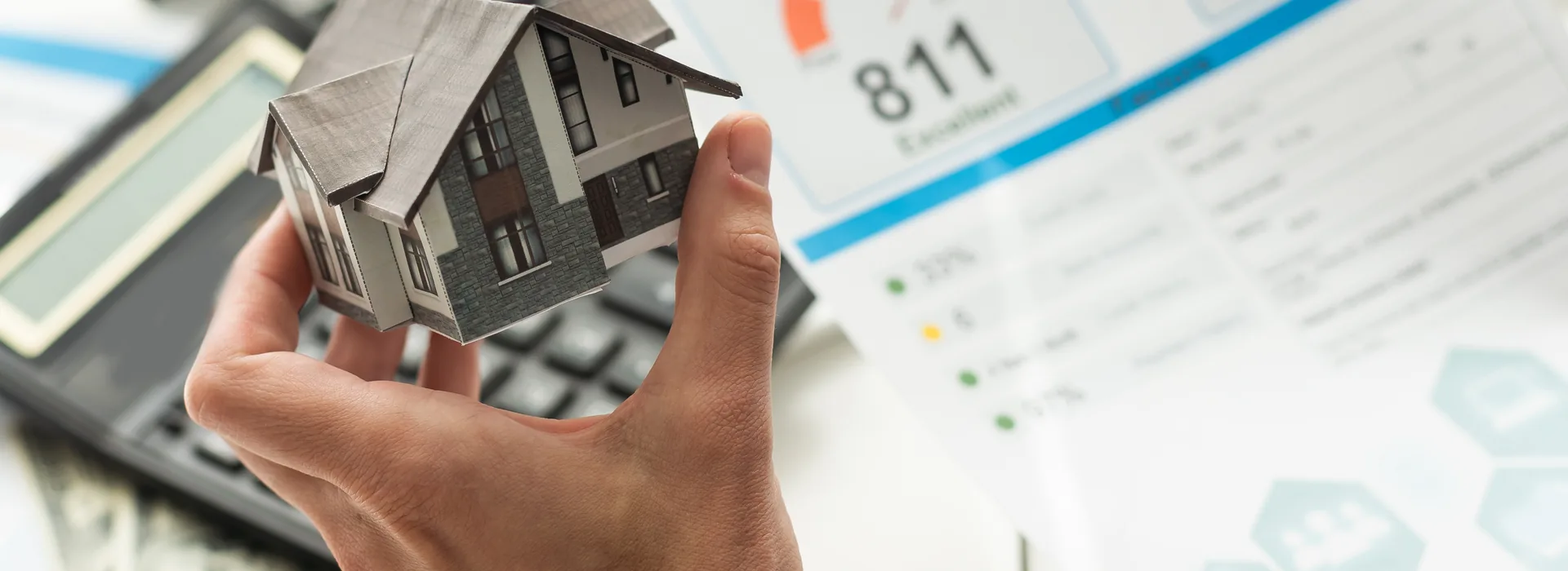 House model held in front of an 811 credit score