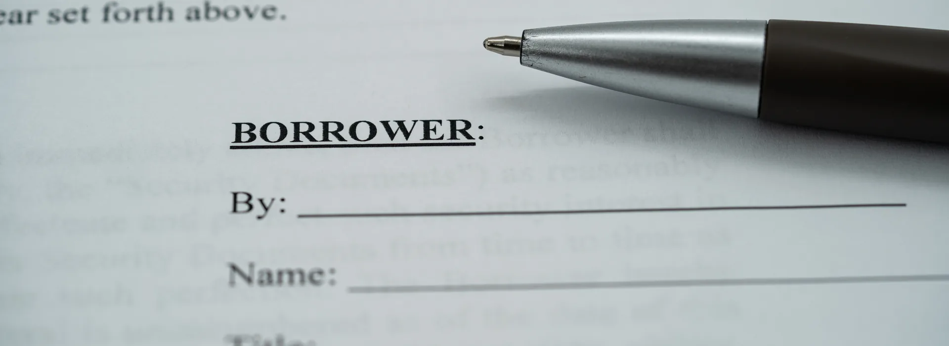 Borrower signature line on a promissory note beside a pen
