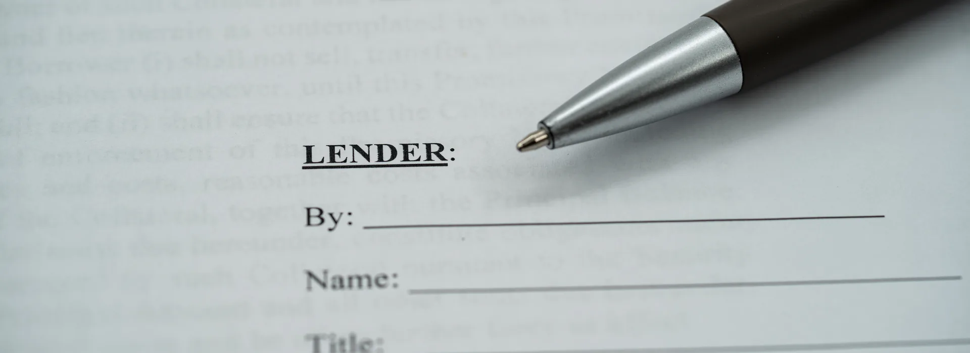 Lender signature line on a loan document beside a pen