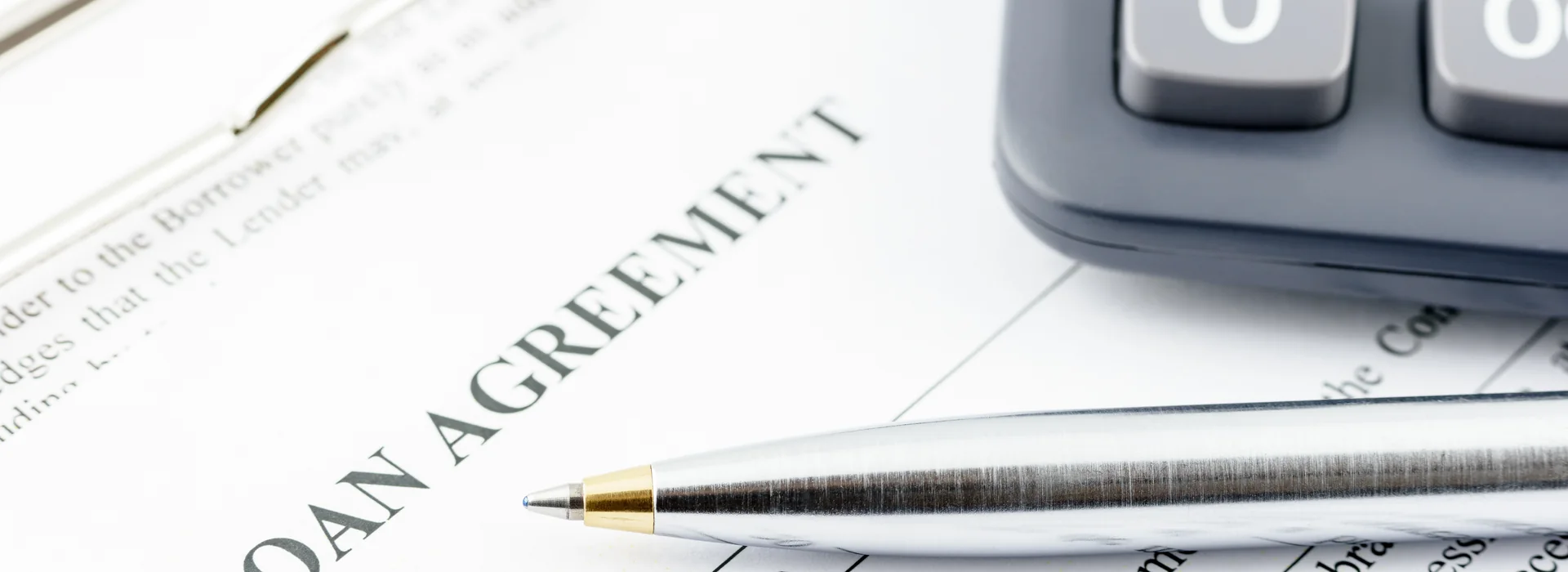 Loan agreement, calculator, and pen for reviewing installment payments