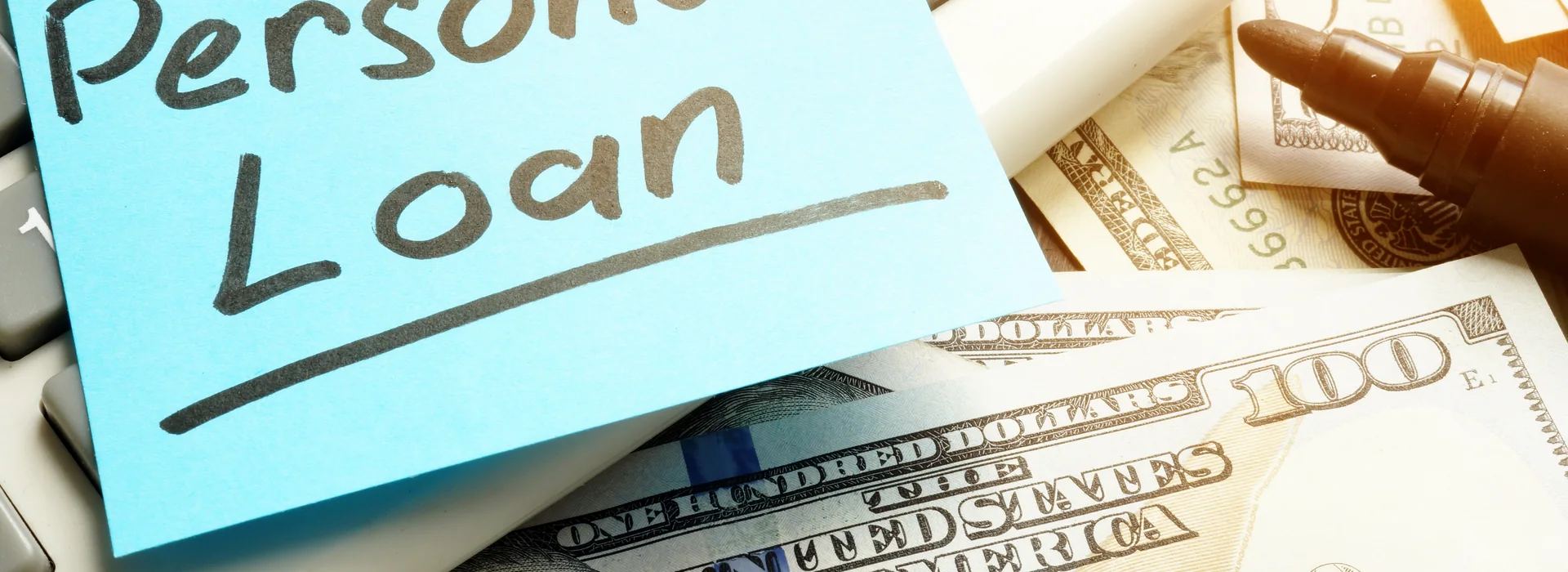 Calculator, cash, and pen used to review a personal loan amount
