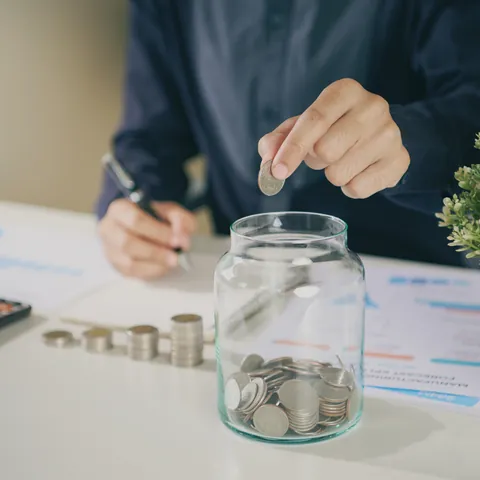 Person placing a coin into an emergency savings jar