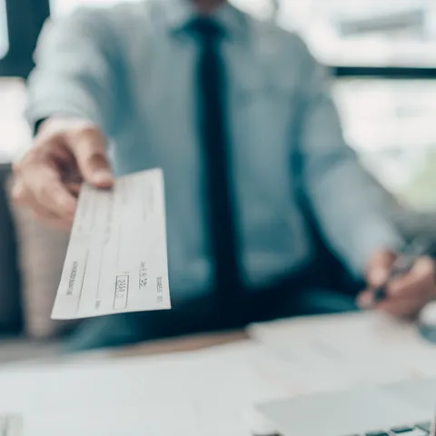 Person handing a check to a customer beside U.S. cash