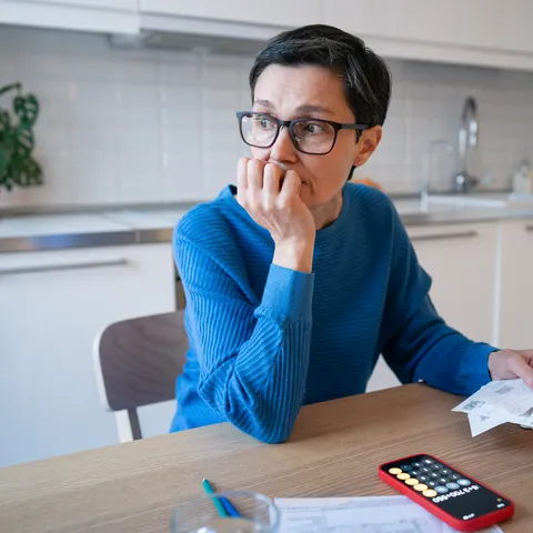 Stressed mature woman surrounded by bills and receipts