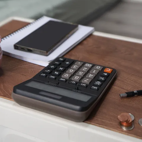 Calculator and smartphone used to compare income and expenses