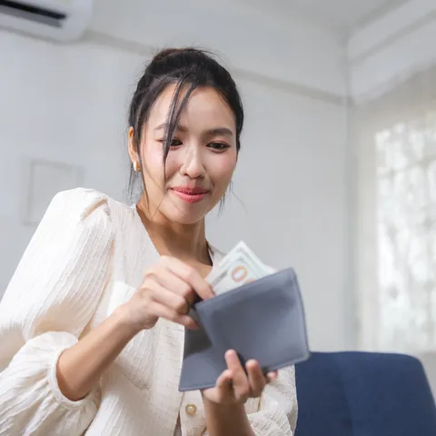 Woman budgeting cash from a wallet at home