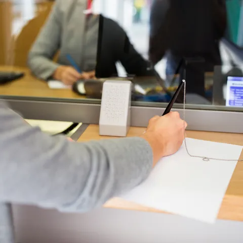 Customer completing a money order form at a bank counter