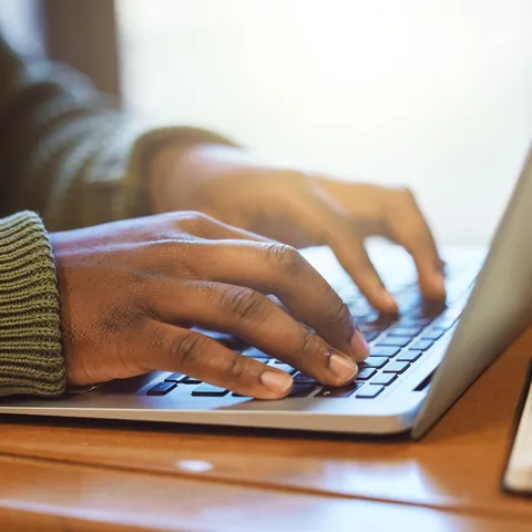 Student typing a scholarship essay on a laptop