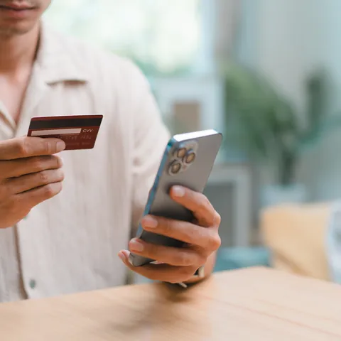 Person using a smartphone and payment card for a digital money transfer