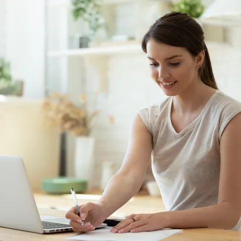 Woman keeping financial records using laptop and calculator