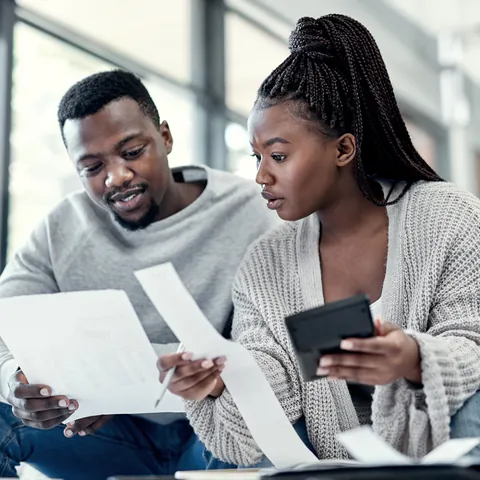 Couple reviewing financial paperwork and loan options at home