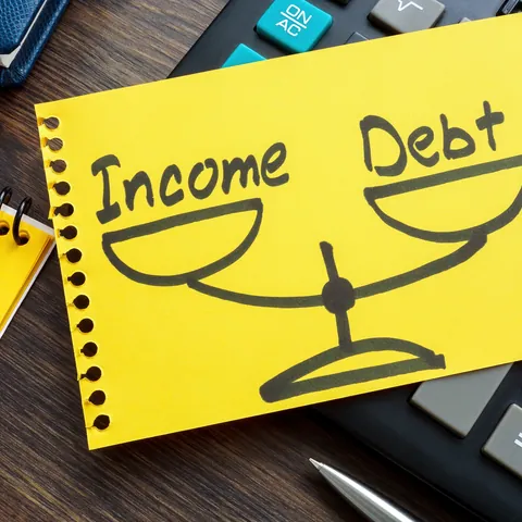 the word debt behind a dollar bill