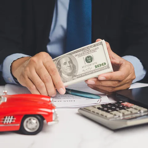 Borrower holding cash beside a toy car while reviewing title loan paperwork