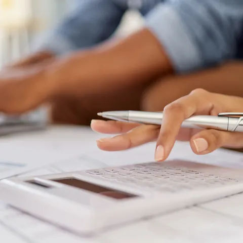 Person using a calculator while reviewing household loan paperwork