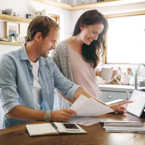 Couple reviewing bills and financial information on a tablet at home