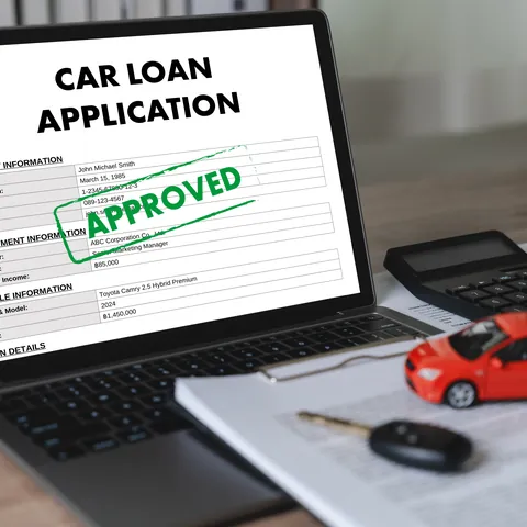 Approved car loan application displayed on a laptop beside a calculator