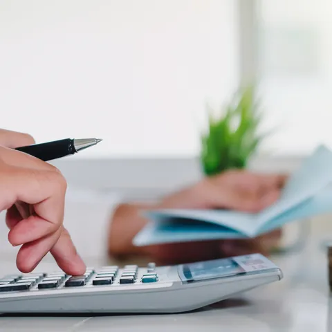 Person using a calculator while reviewing installment loan paperwork
