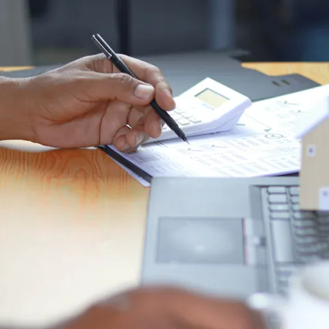 Financial professional reviewing personal loan documents beside house models