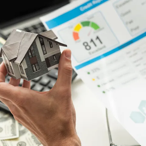 House model held in front of an 811 credit score