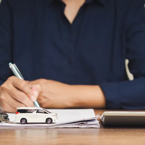 Borrower signing a collateral loan agreement beside car keys