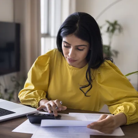 Freelancer reviewing income records and invoices with a calculator