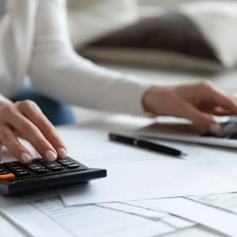 Woman comparing debt repayment options with bills and a calculator