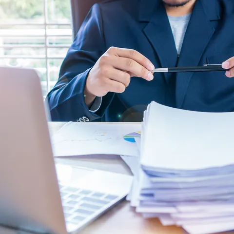 Person reviewing application documents with a calculator and laptop