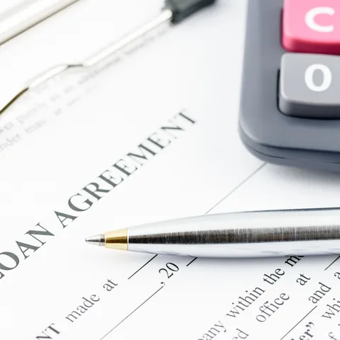 Loan agreement, calculator, and pen for reviewing installment payments