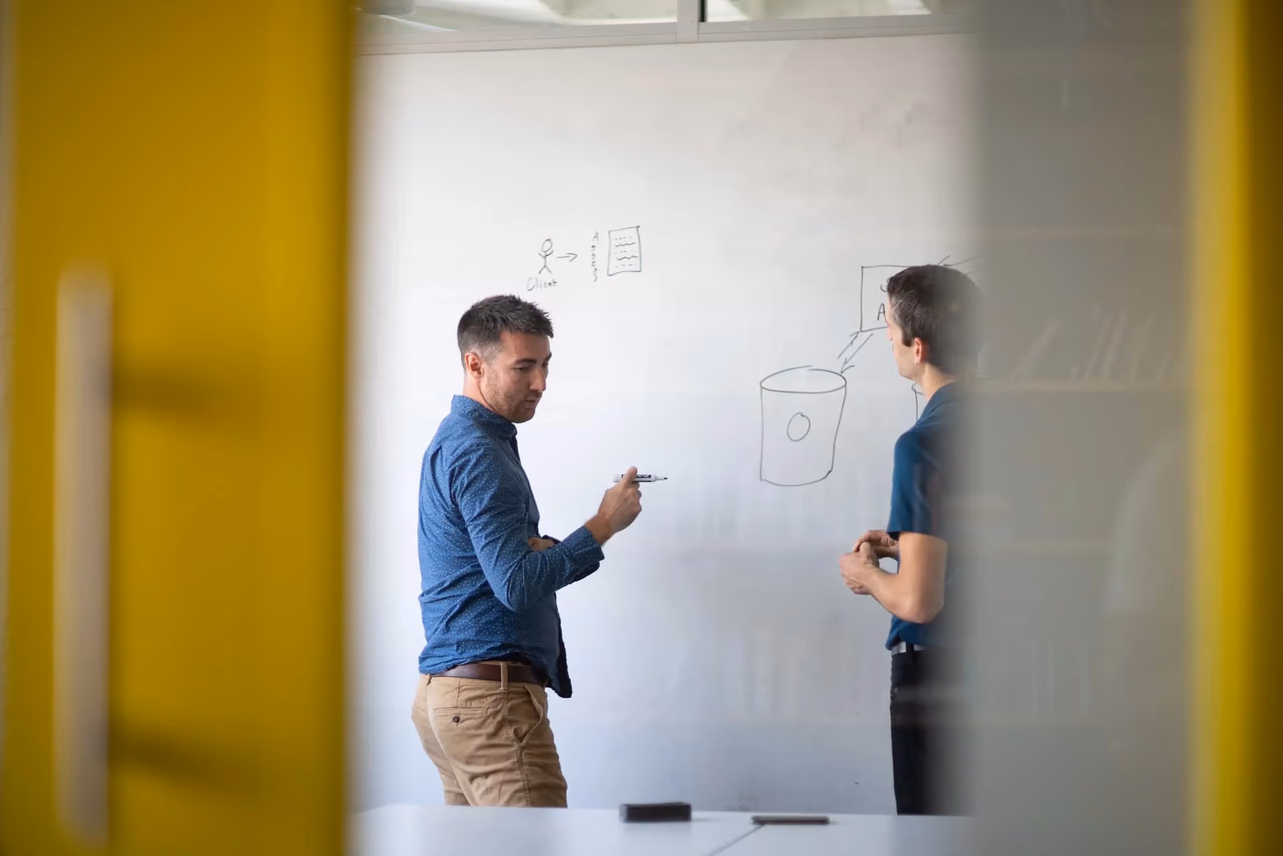 Medium shot of Luke Golden and Matt Campbell, Whiteboard employees, conferring in front of a whiteboard.
