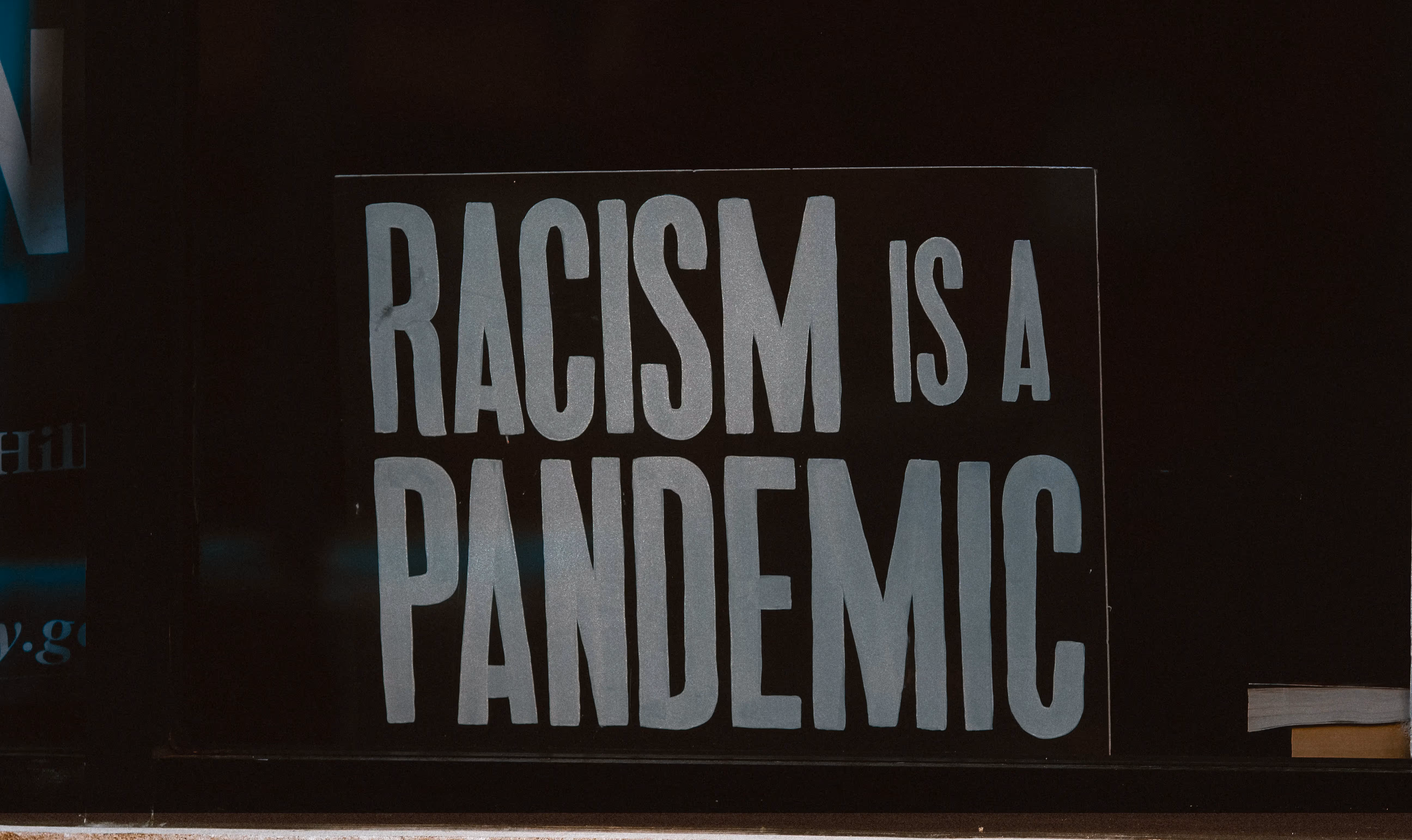 Poster reading, "Racism is a Pandemic." Original image by Jon Tyson.