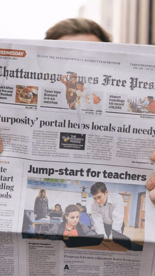 A man holds up a newspaper with a headline about Purposity