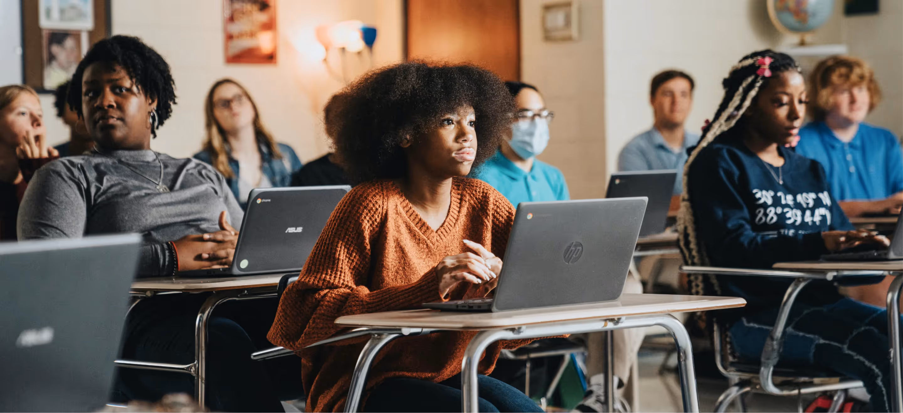 Students sitting in a classroom, working on laptop computers.