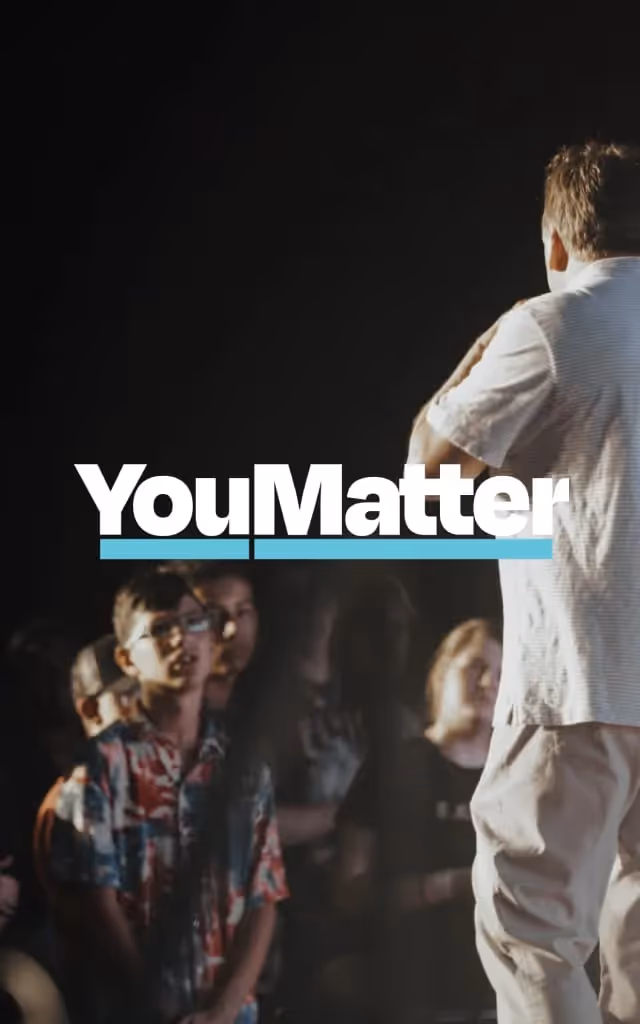 Dean Sikes speaks from a stage to teens.