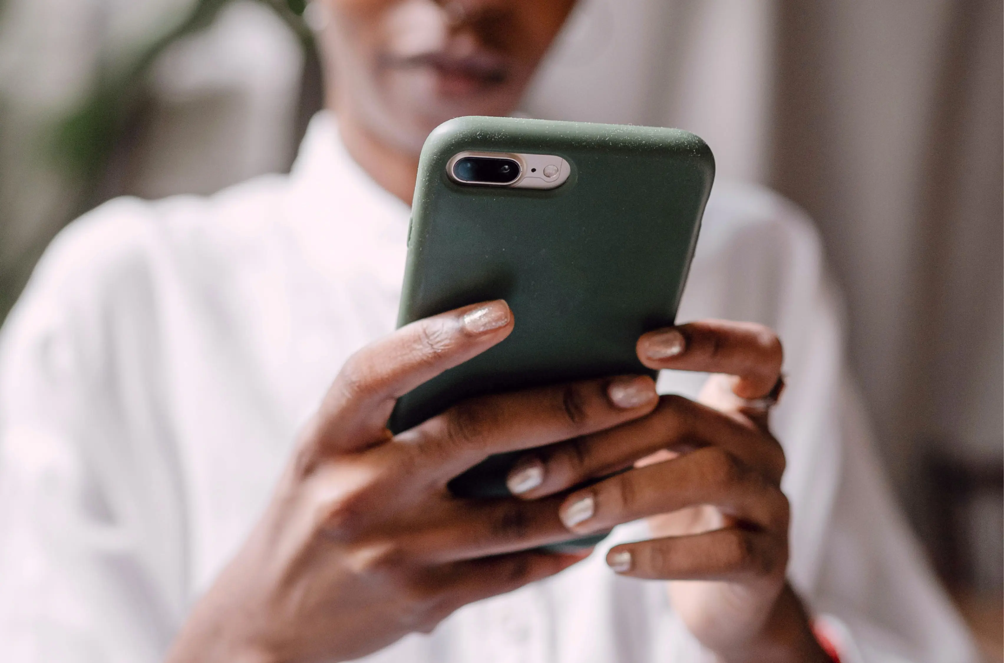 A person holding a mobile device with green case.