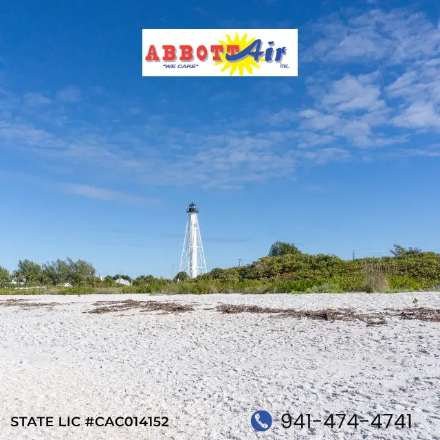 White lighthouse (Gasparilla lighthouse) by green shrubbery under blue sky on a sandy beach with Abbott Air logo and phone number.